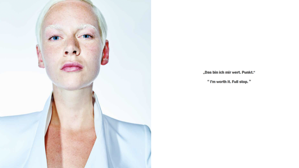 Eine junge Frau mit kurzen weißen Haaren blickt mit kühlen blauen Augen in die Kamera.