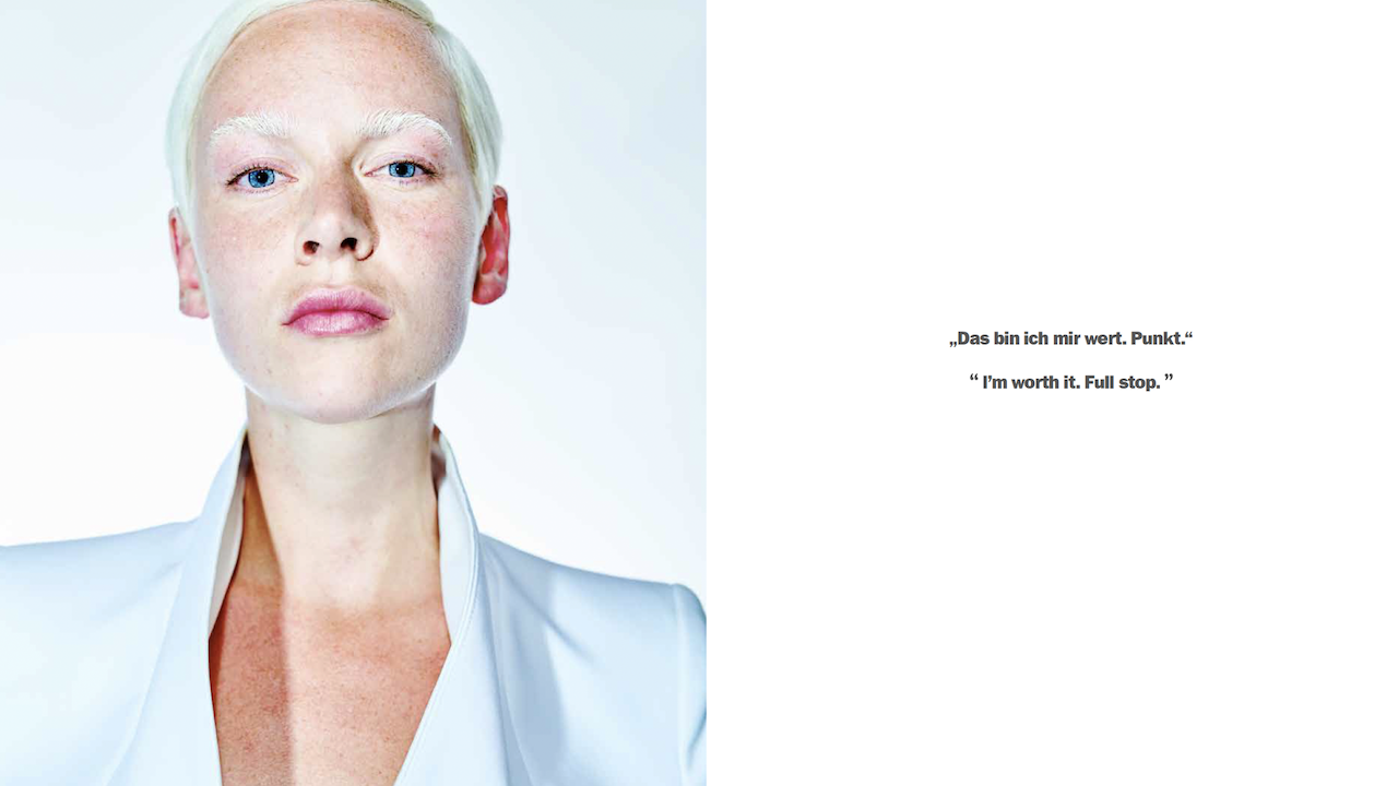 Eine junge Frau mit kurzen weißen Haaren blickt mit kühlen blauen Augen in die Kamera.